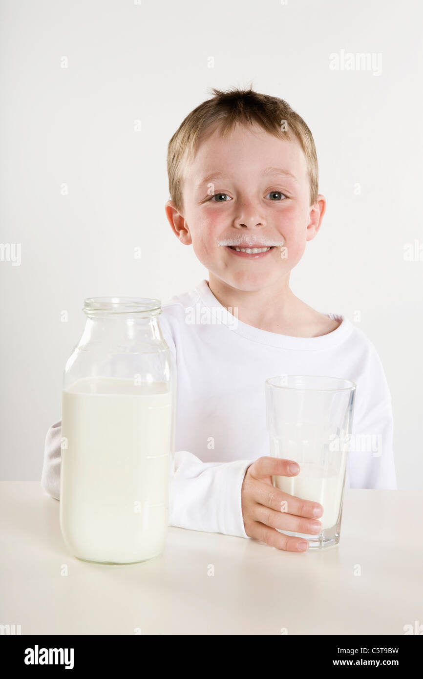 Ragazzo (6-7) tenendo un bicchiere di latte, sorridente, ritratto Foto Stock