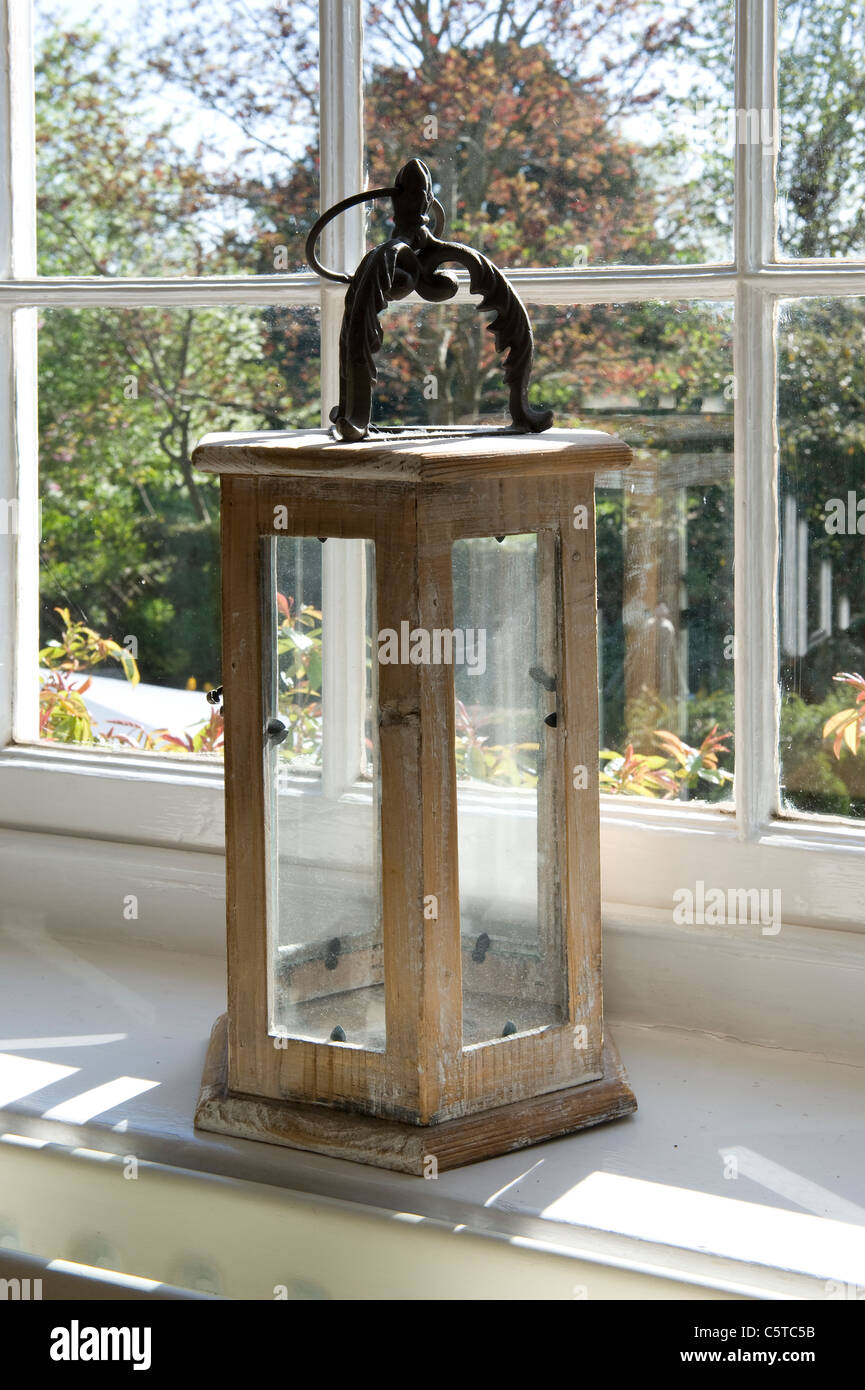 Legno di antiquariato lanterna a candela sul davanzale della finestra con vista giardino in background Foto Stock