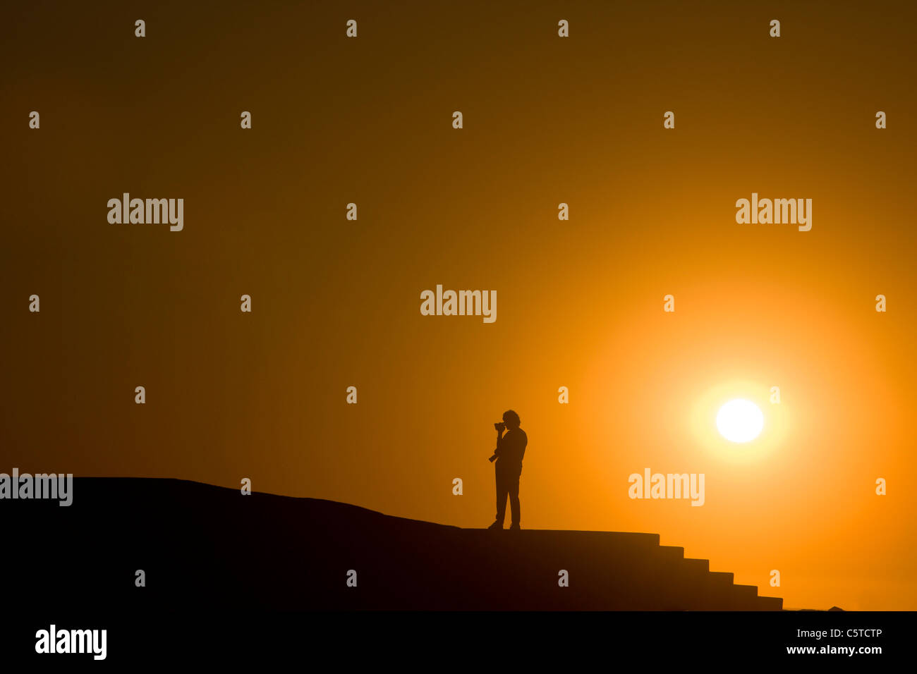 Un turista solitario film la scena circostante come il sole tramonta. Swakopmund, Namibia. Foto Stock