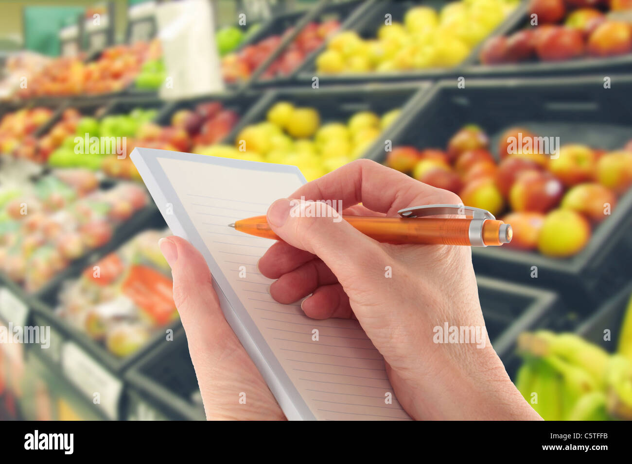 Mano con penna a scrivere una lista della spesa da supermercato frutta Foto Stock