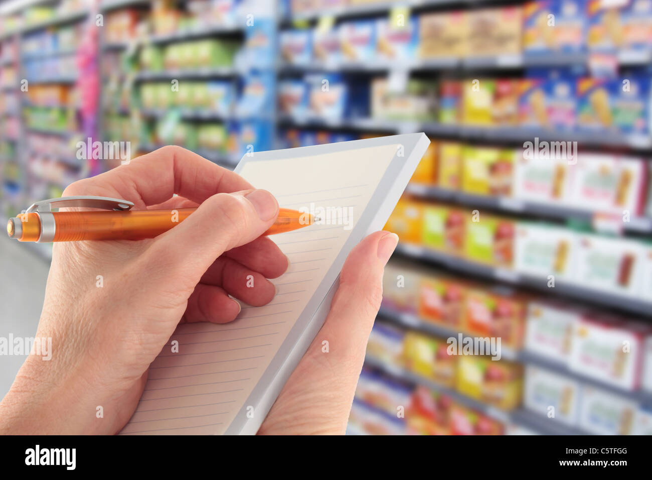 La scrittura di un elenco di acquisti in un supermercato Foto Stock