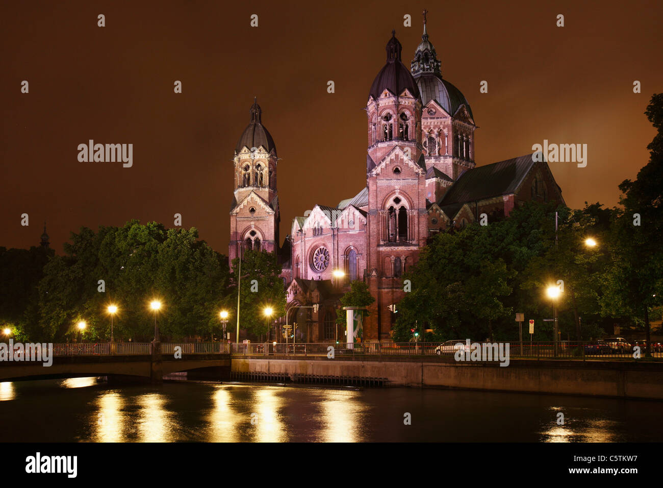 In Germania, in Baviera, Monaco di Baviera, vista di st lukas chiesa dal fiume Isar di notte Foto Stock