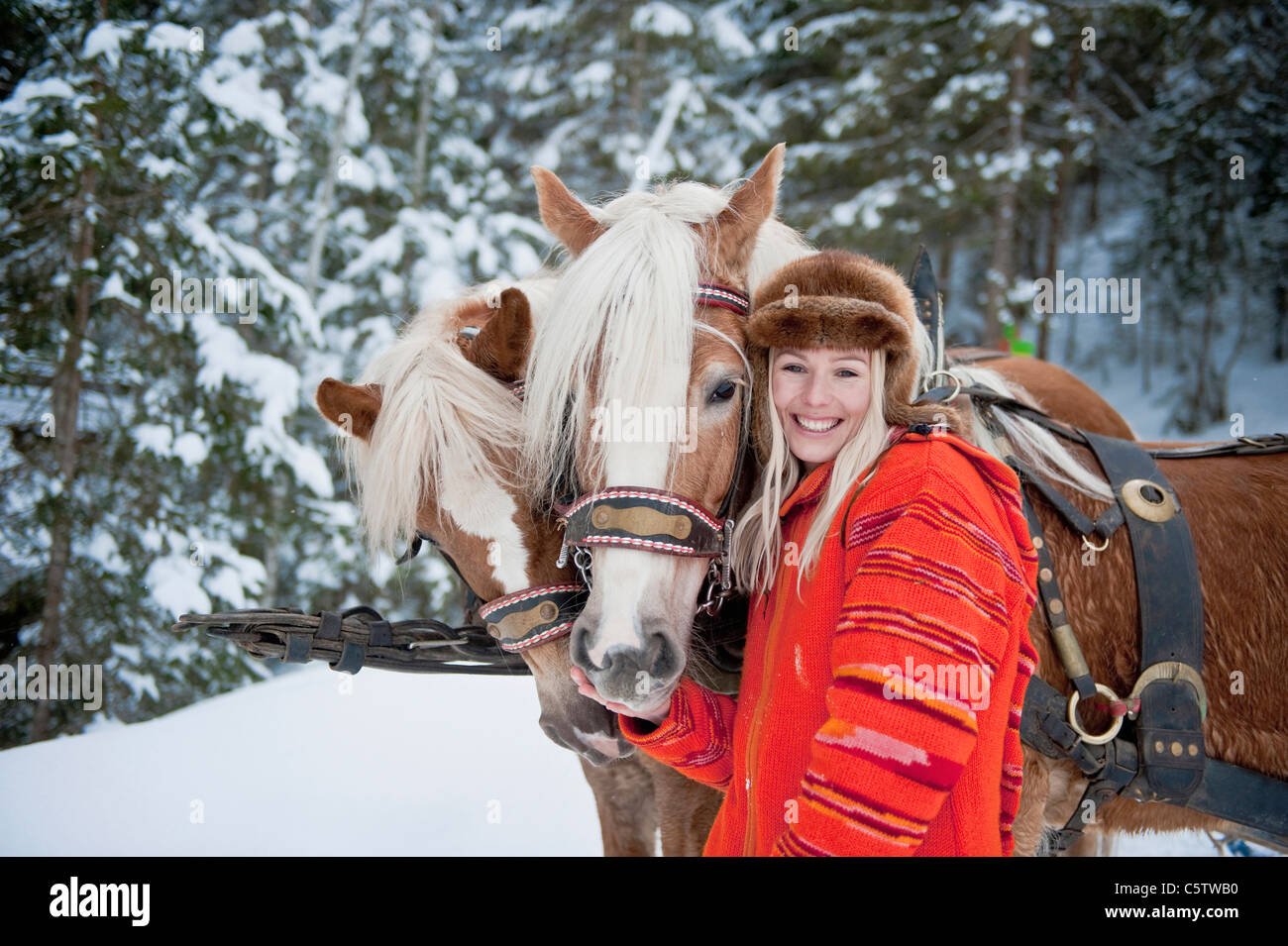Austria, Salzburger Land, giovane donna in piedi accanto a cavalli, sorridente, ritratto Foto Stock