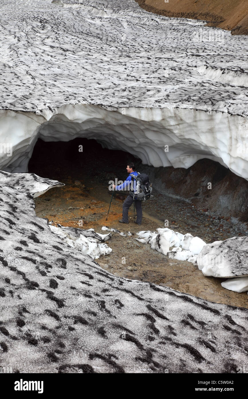 Escursionista guardando all' ingresso di un crollato caverna di ghiaccio sul Laugavegur Hiking Trail Islanda Foto Stock