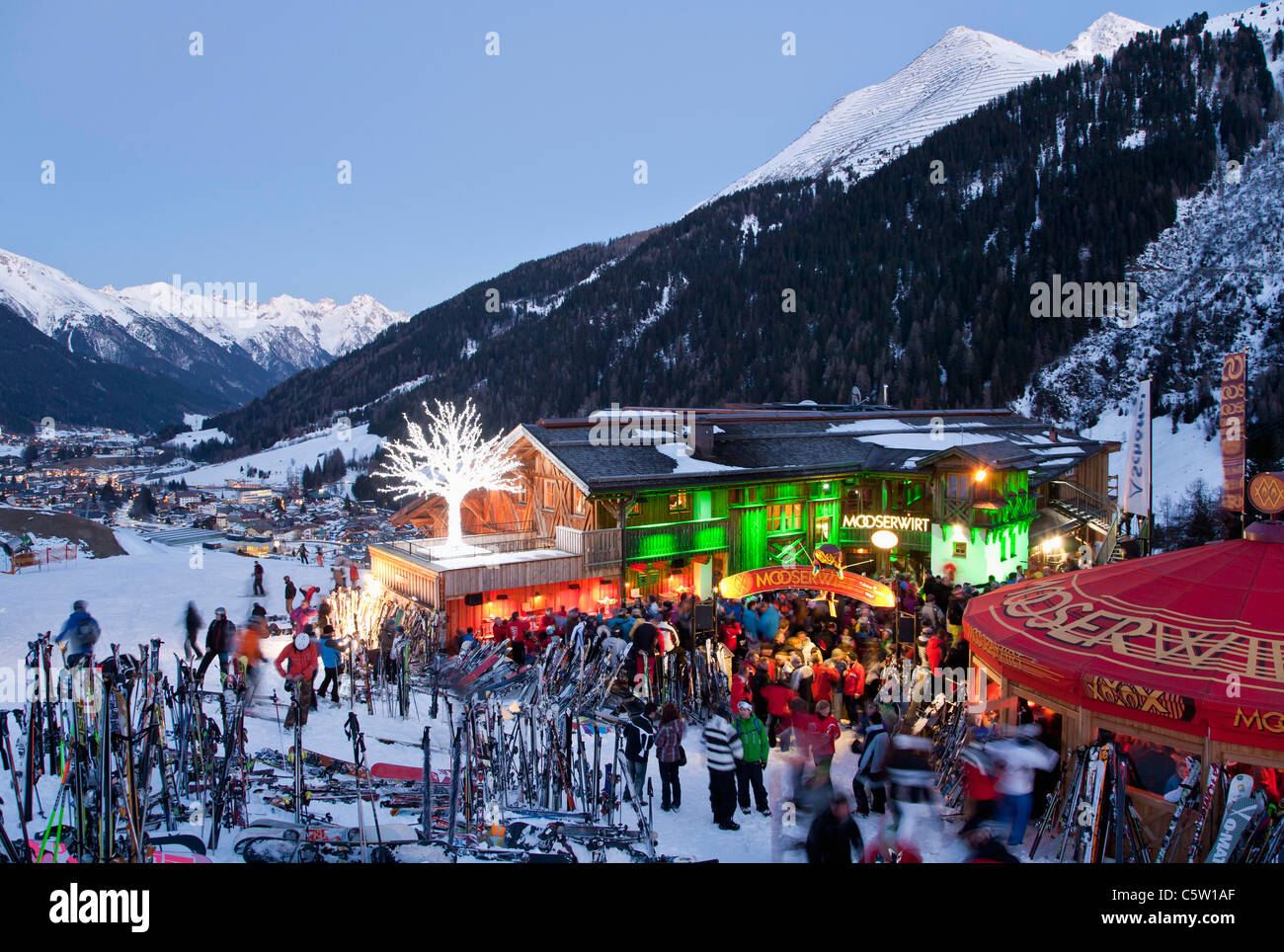 Austria, Tirolo, St. Anton am Arlberg, Mooserwirt, persone sciare vicino rifugio sciistico in inverno al tramonto Foto Stock