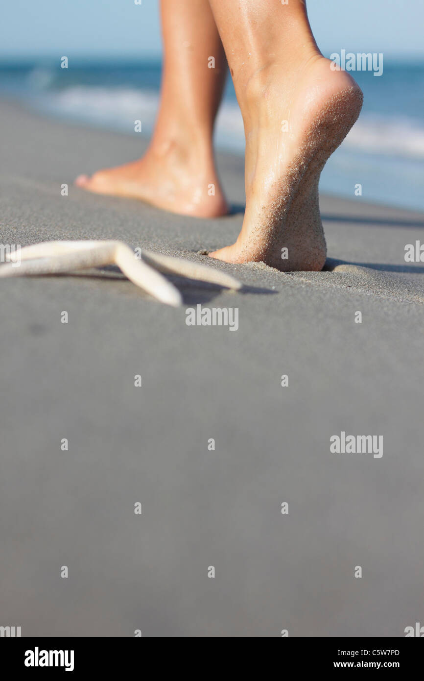 L'Italia, Sardegna, donna di piedi camminando sulla spiaggia sabbiosa Foto Stock