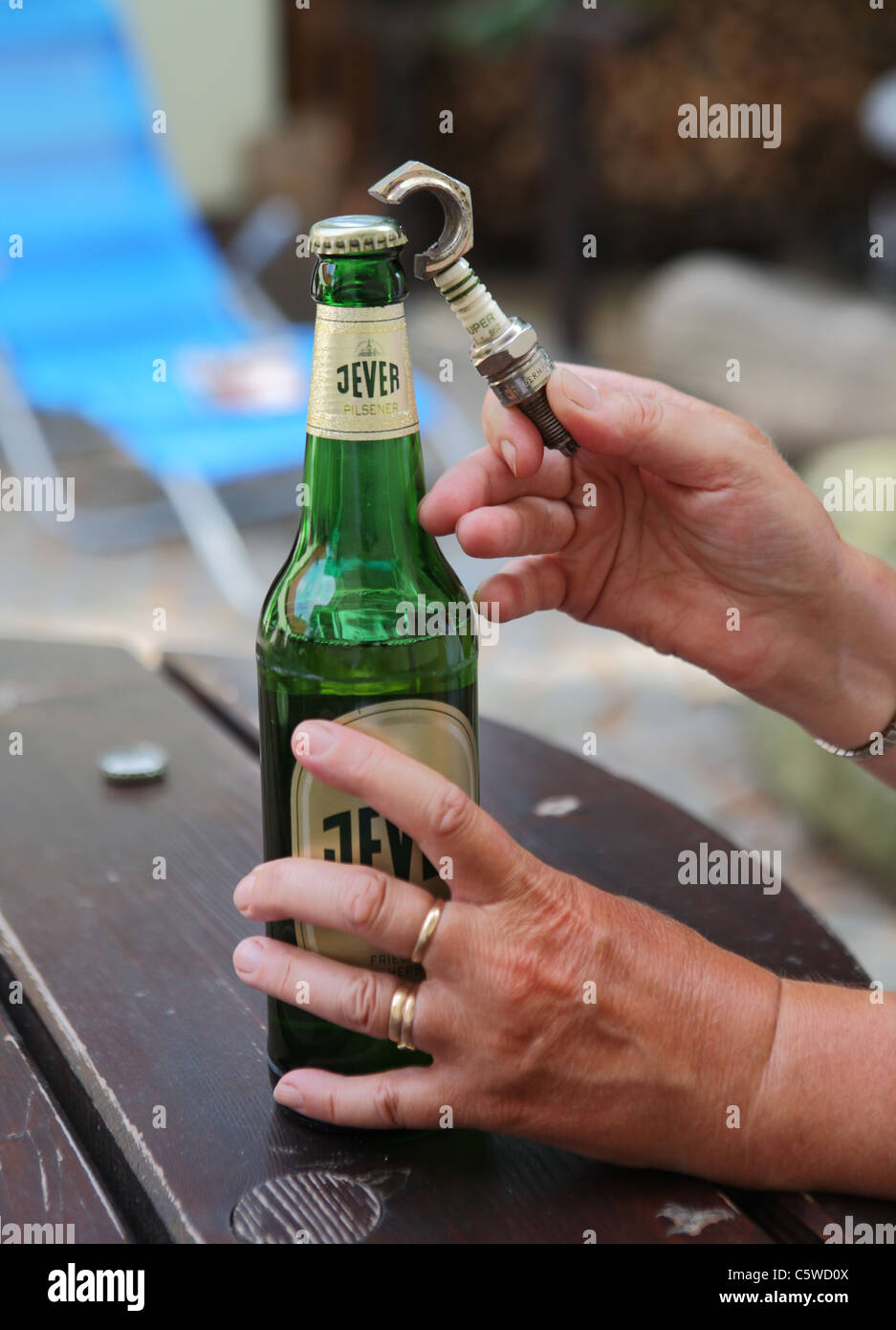Apertura di una bottiglia di tedesco Jever birra utilizzando una novità apribottiglie basato su una candela di accensione Foto Stock