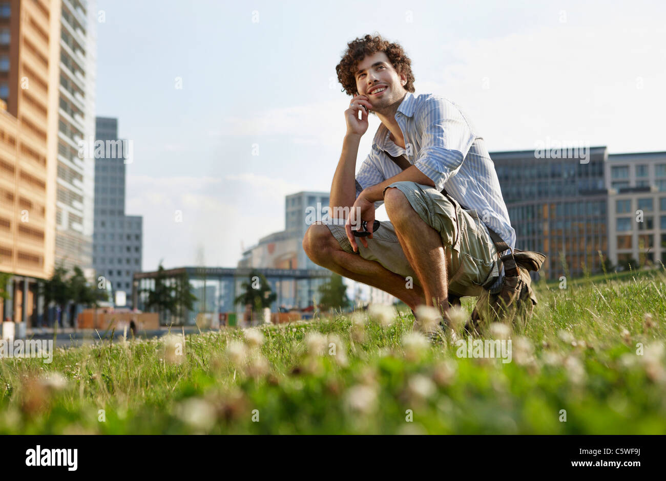Germania, Berlino, giovane utilizzando il telefono cellulare, sorridente, ritratto Foto Stock