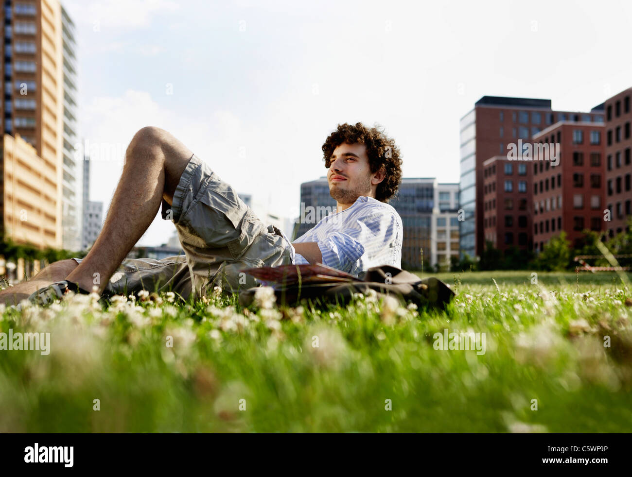 Germania, Berlino, uomo rilassarsi sul prato, in background alti edifici Foto Stock