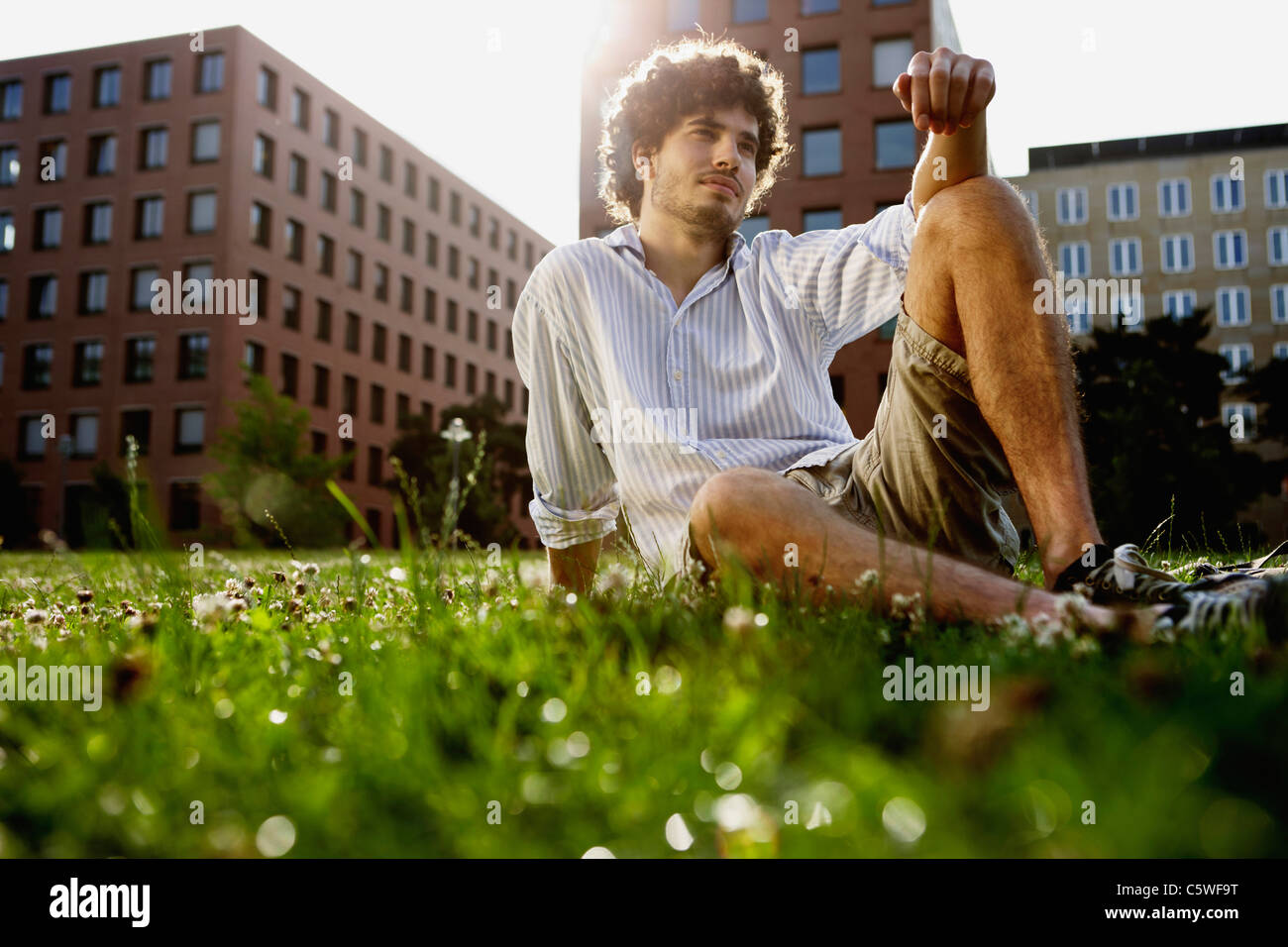 Germania, Berlino, giovane uomo rilassarsi sul prato, in background alti edifici Foto Stock