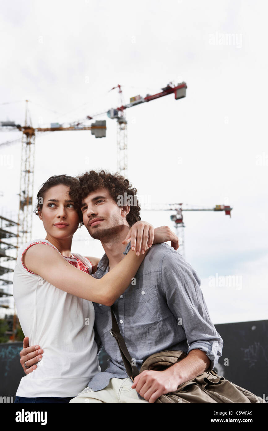 Germania Berlino giovane coppia nella parte anteriore del nuovo edificio, gru in background Foto Stock