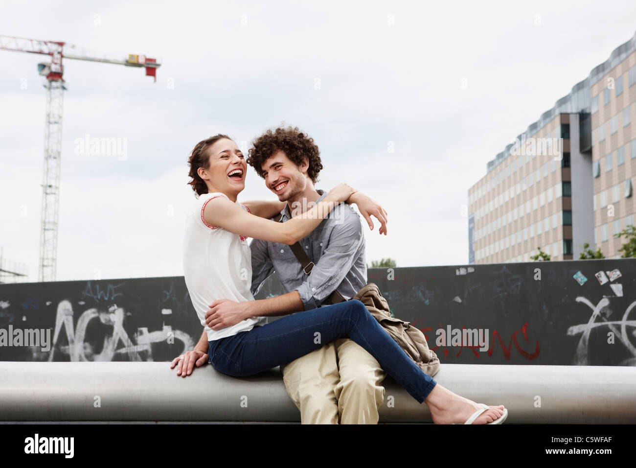 Germania Berlino giovane coppia nella parte anteriore del nuovo edificio, gru in background Foto Stock