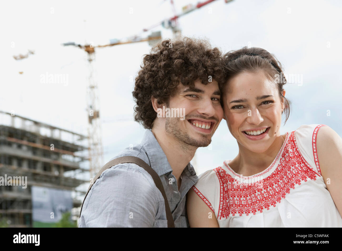 Germania Berlino giovane coppia nella parte anteriore del nuovo edificio, gru in background Foto Stock