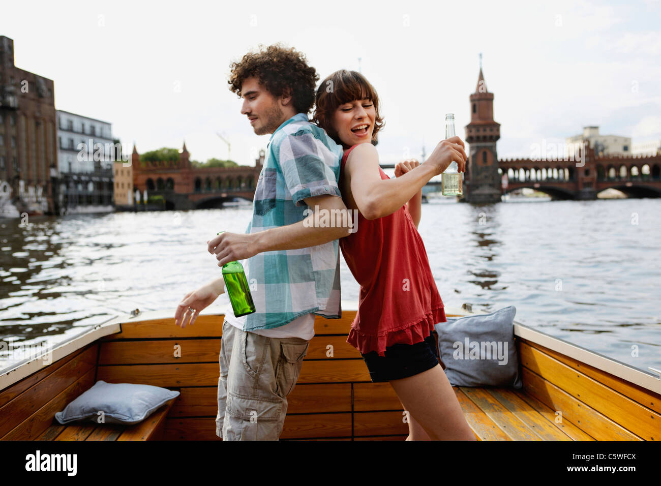 Germania, Berlino, giovane coppia in motoscafo, tenendo le bottiglie, in piedi di schiena Foto Stock