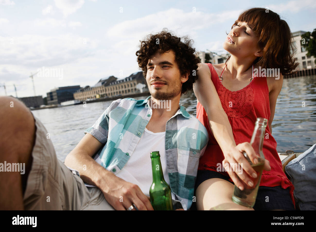 Germania Berlino giovane coppia su imbarcazione a motore, tenendo le bottiglie, ritratto, close-up Foto Stock