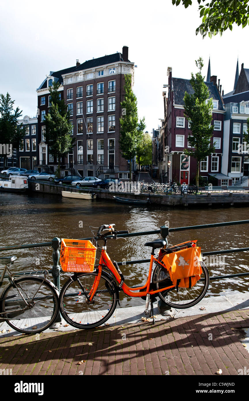 Orange bike incatenati al ponte sul canale Singel in Amsterdam. Il colore arancione è il colore della famiglia reale nei Paesi Bassi. Foto Stock