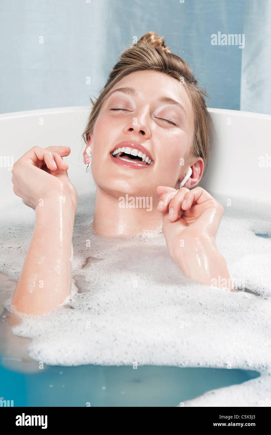 Giovane donna in vasca da bagno ascoltando musica Foto stock - Alamy