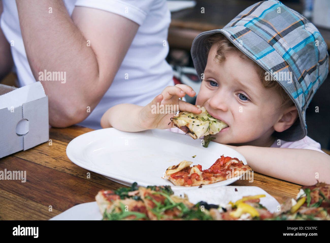 Germania, Berlino, ragazzo (3-4) mangiando pezzi di pizza all'aperto, ritratto Foto Stock