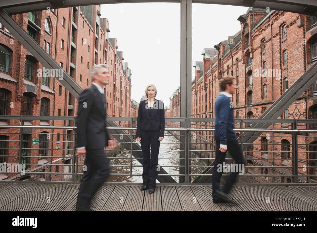 Germania, Amburgo, due imprenditori attraversando il ponte, imprenditrice in background Foto Stock