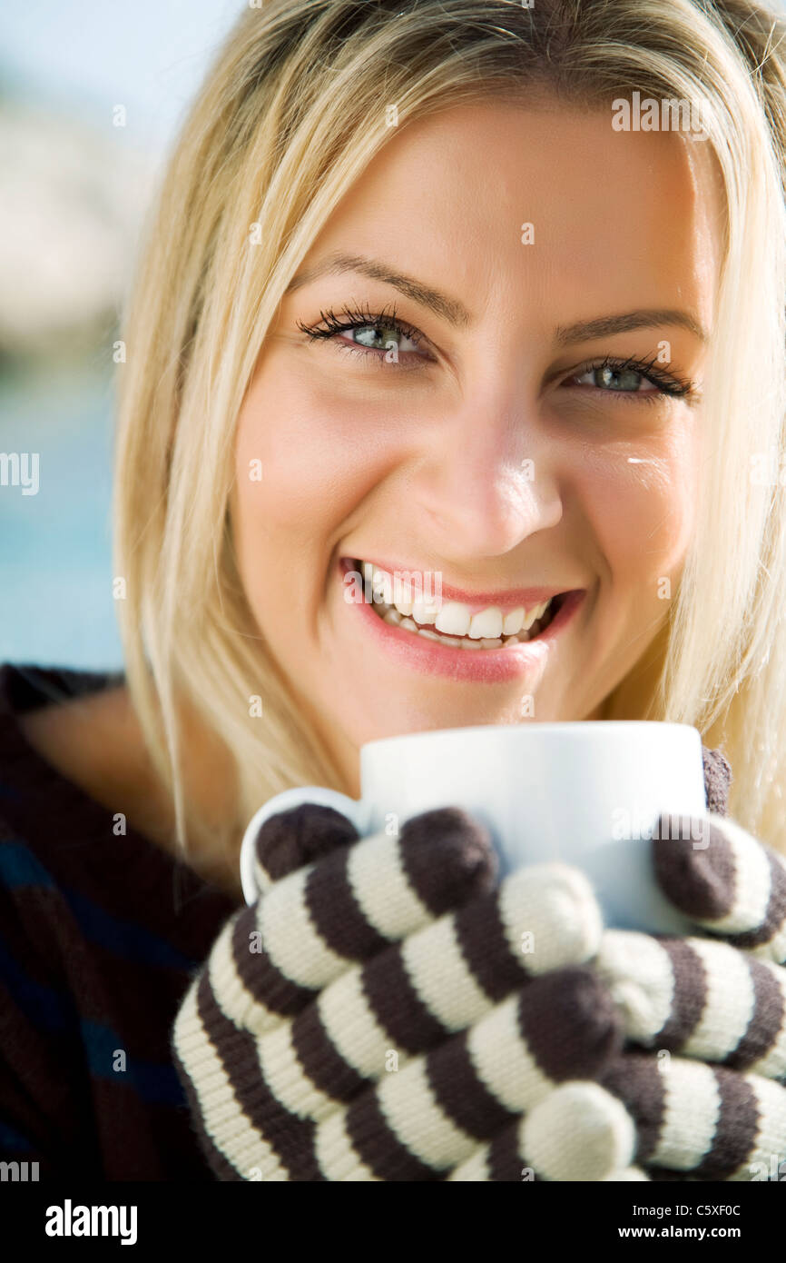 Donna sorridente con una bevanda calda Foto Stock