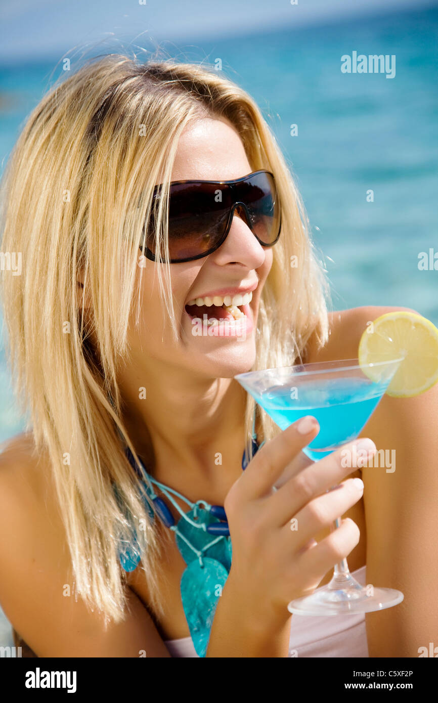 Ridendo donna bevendo cocktail in riva al mare Foto Stock