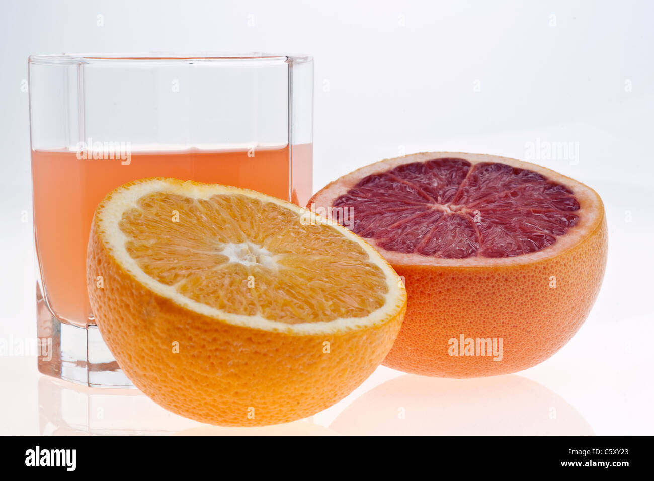 Due metà di pompelmo e succo di frutta in vetro su bianco Foto Stock