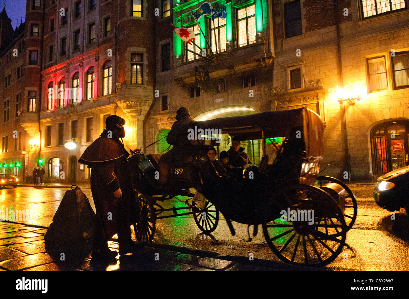 Fairmont le Château Frontenac Night Horse Drawn Carriage Quebec City Canada // QUEBEC CITY, Canada - l'iconico Fairmont le Château Frontenac, arroccato sulla cima di Cap Diamant, domina lo skyline di Quebec City di notte mentre passa una carrozza trainata da cavalli. Completato nel 1893 come uno dei grandi hotel della Canadian Pacific Railway, la struttura in stile castello rappresenta l'hotel più fotografato al mondo. Il sito Patrimonio dell'Umanità dell'UNESCO offre vedute panoramiche del fiume San Lorenzo dalla sua posizione a 54 metri (177 piedi) sopra l'acqua. Foto Stock