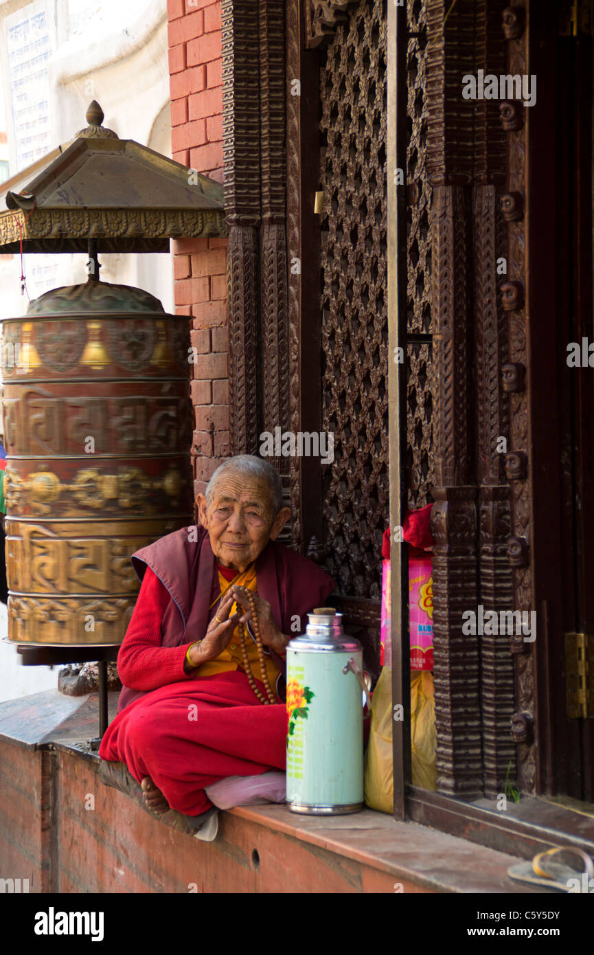 Vecchia donna Nepalese pregando seduto davanti a un tempio, Kathmandu, Nepal Foto Stock