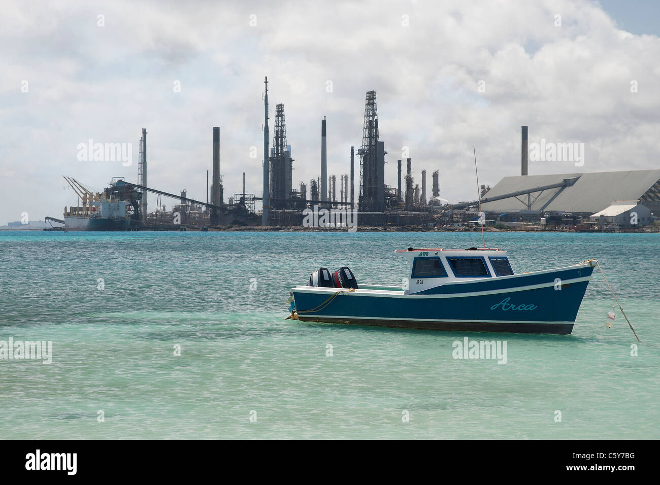 Barca da pesca in una baia con il valero raffineria di petrolio in background, Aruba, Antille olandesi Foto Stock