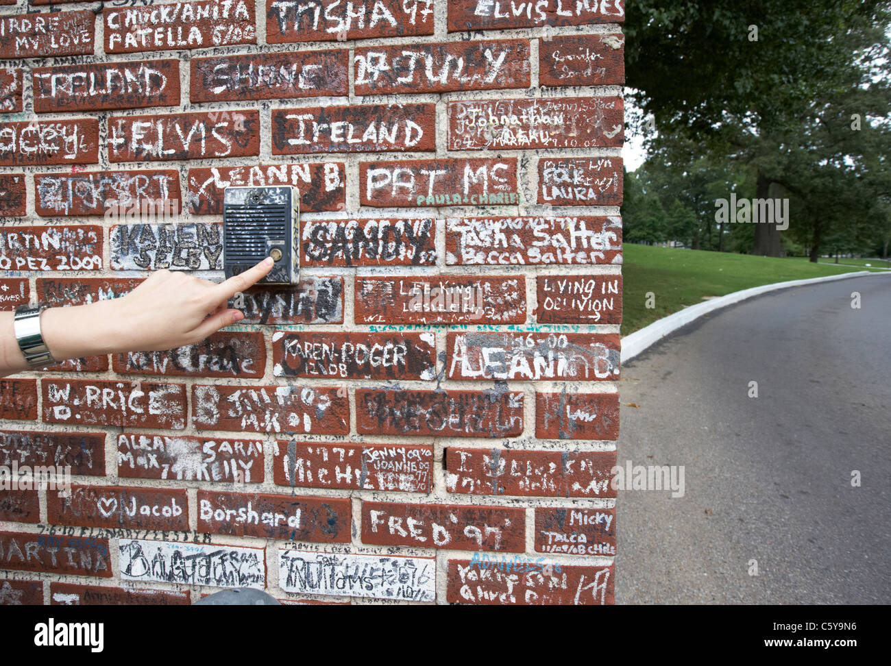 Womans spingendo a mano il vecchio pulsante interfono su muro coperto di graffiti al di fuori di Graceland Memphis, Tennessee, Stati Uniti d'America Foto Stock