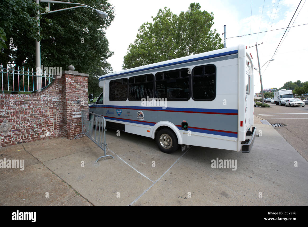 Tour bus guida attraverso i cancelli di graceland oltre la parete coperto di graffiti al di fuori di Graceland Memphis, Tennessee, Stati Uniti d'America Foto Stock