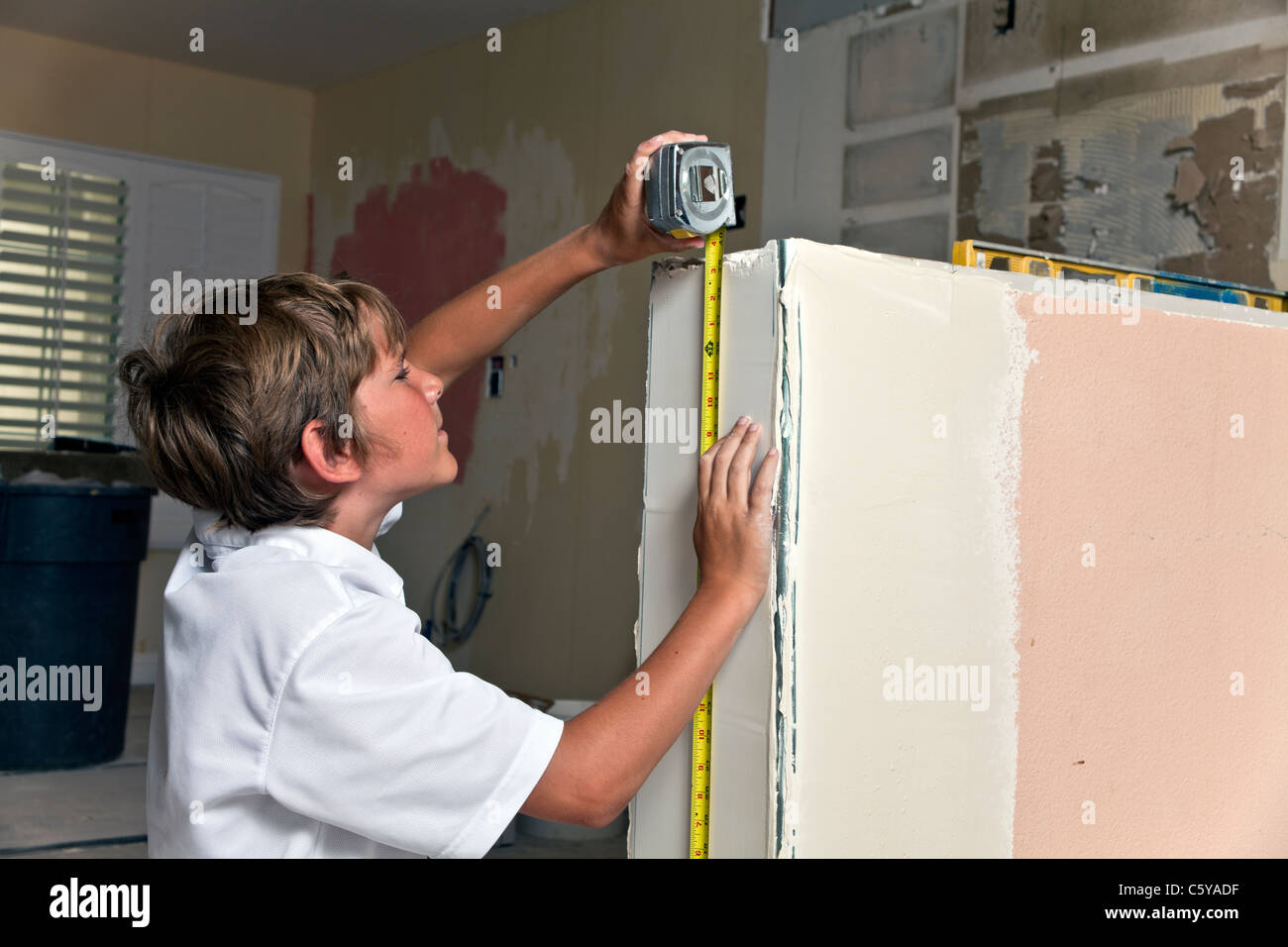 11-12 anni vecchio ragazzo caucasico aiutando l'esperienza di lavoro misure nastro di misurazione pony parete durante la cucina rimodellare. Signor © Myrleen Pearson Foto Stock