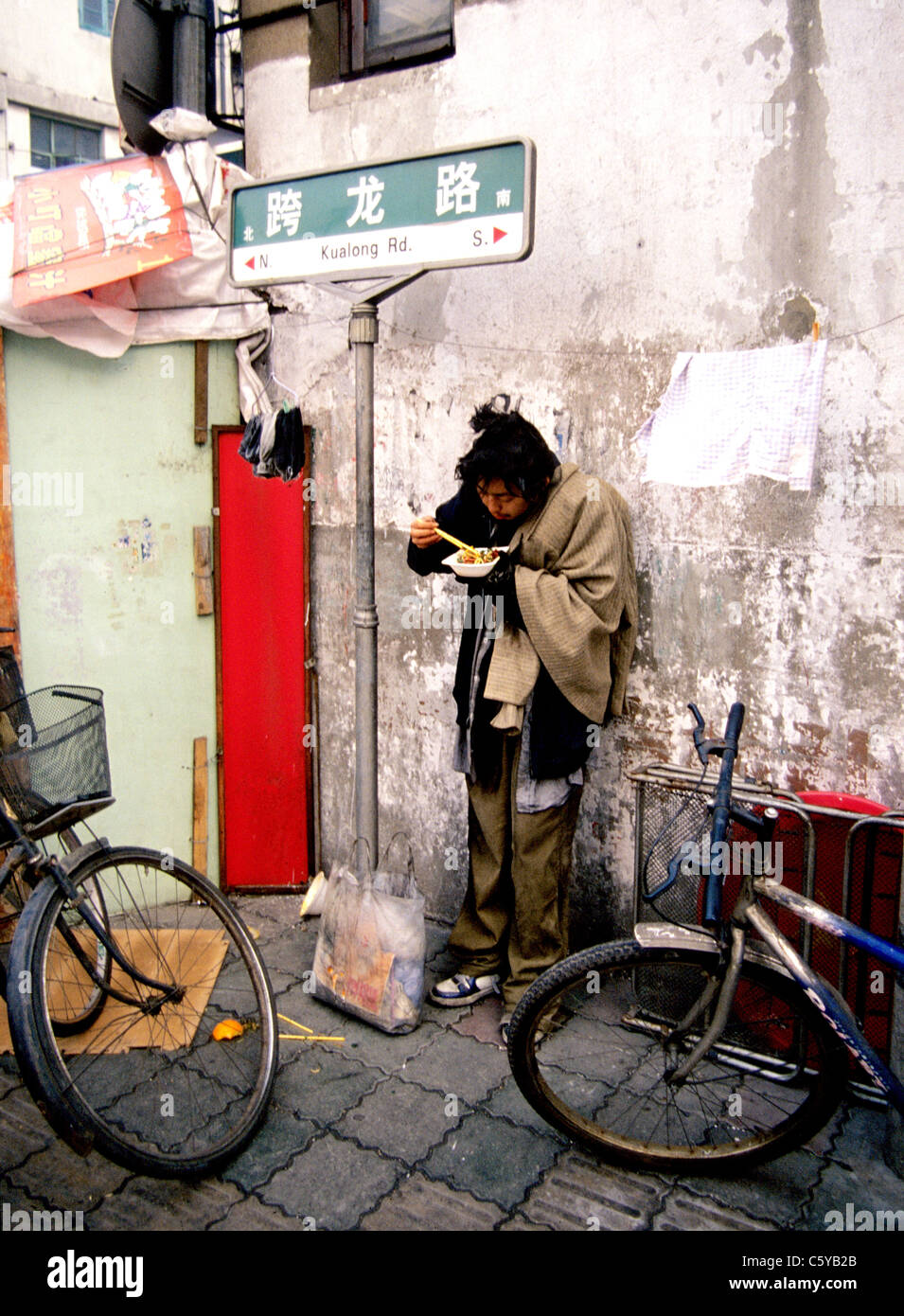 Senzatetto uomo mangia nel vicolo di Shanghai in Cina Foto Stock