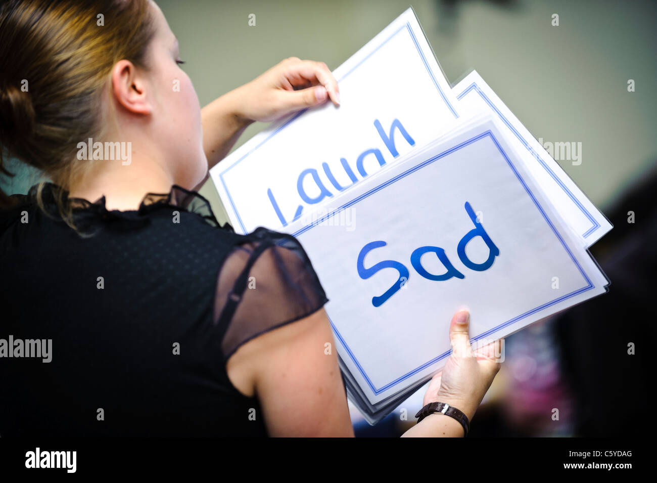 Femmina insegnante caucasica tenendo su schede di cue dicendo ridere e triste Foto Stock