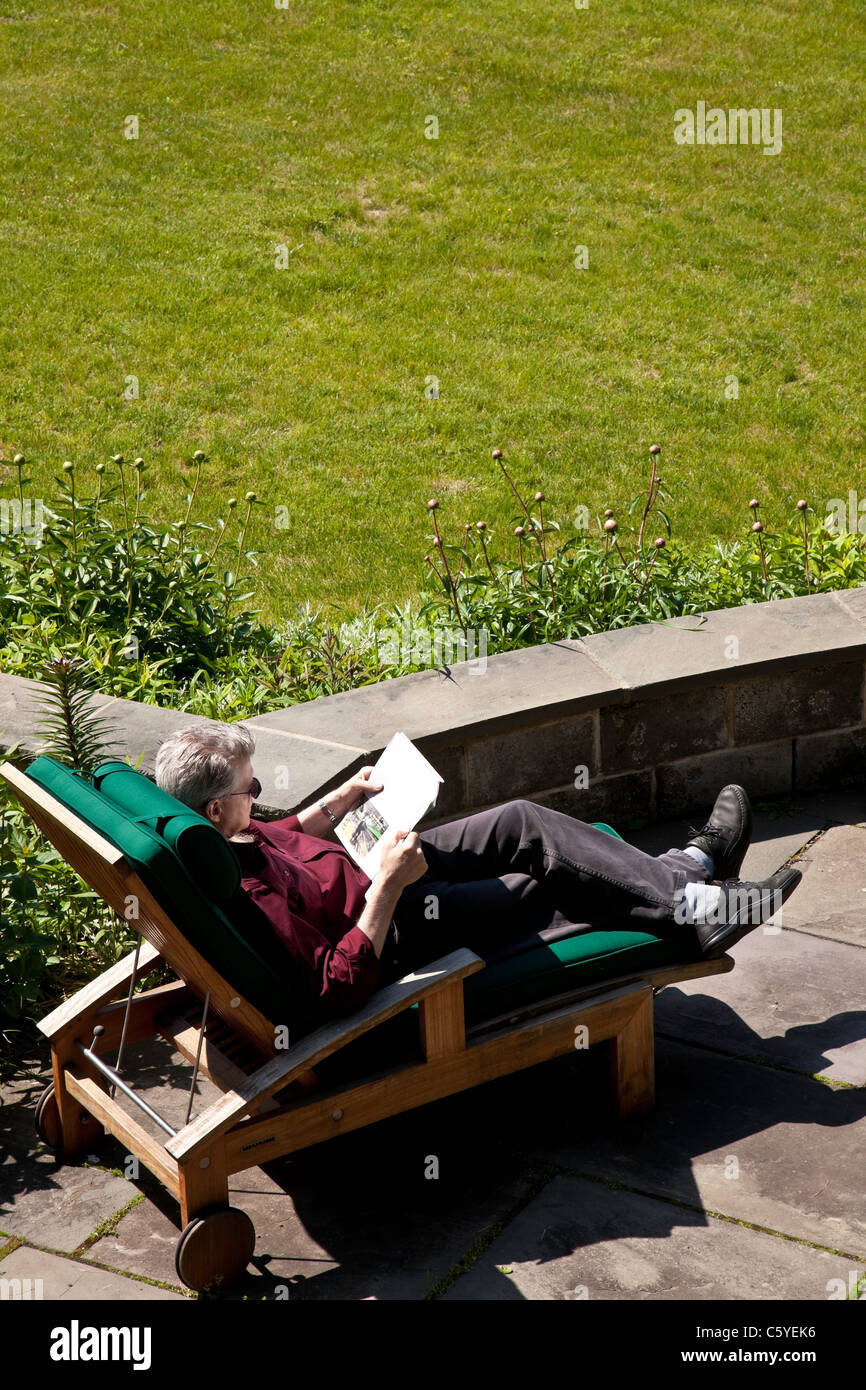 Uomo maturo rilassante sulla chaise lounge chair sul ponte lastricato Foto Stock