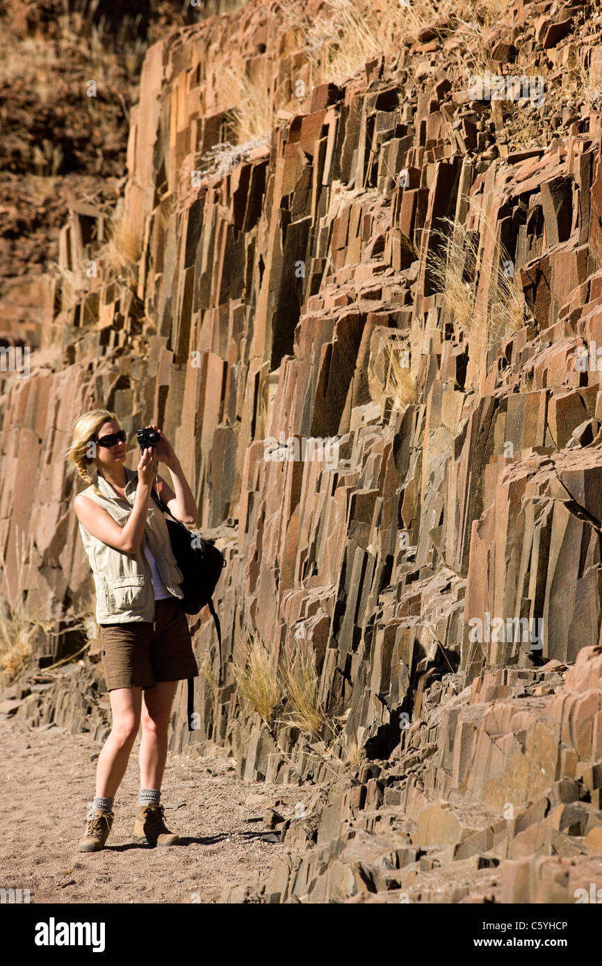 Un turista femminile prende alcune foto dell'organo a canne, Twyfelfontein, Damaraland, Kaokoveld, Namibia. Foto Stock