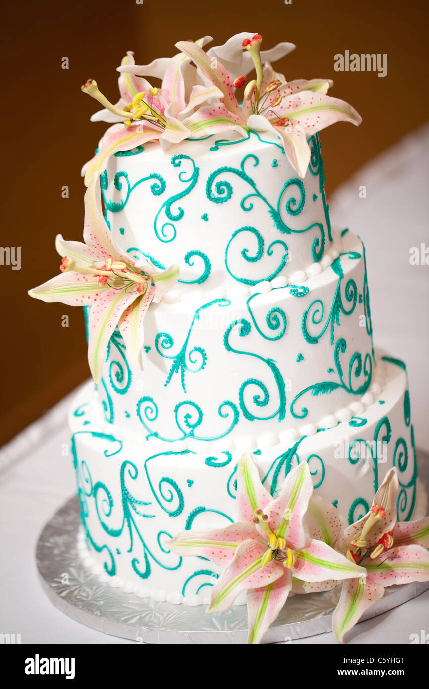 Su tre livelli di bianco e teal torta nuziale coperta con fondente commestibili gigli. Foto Stock