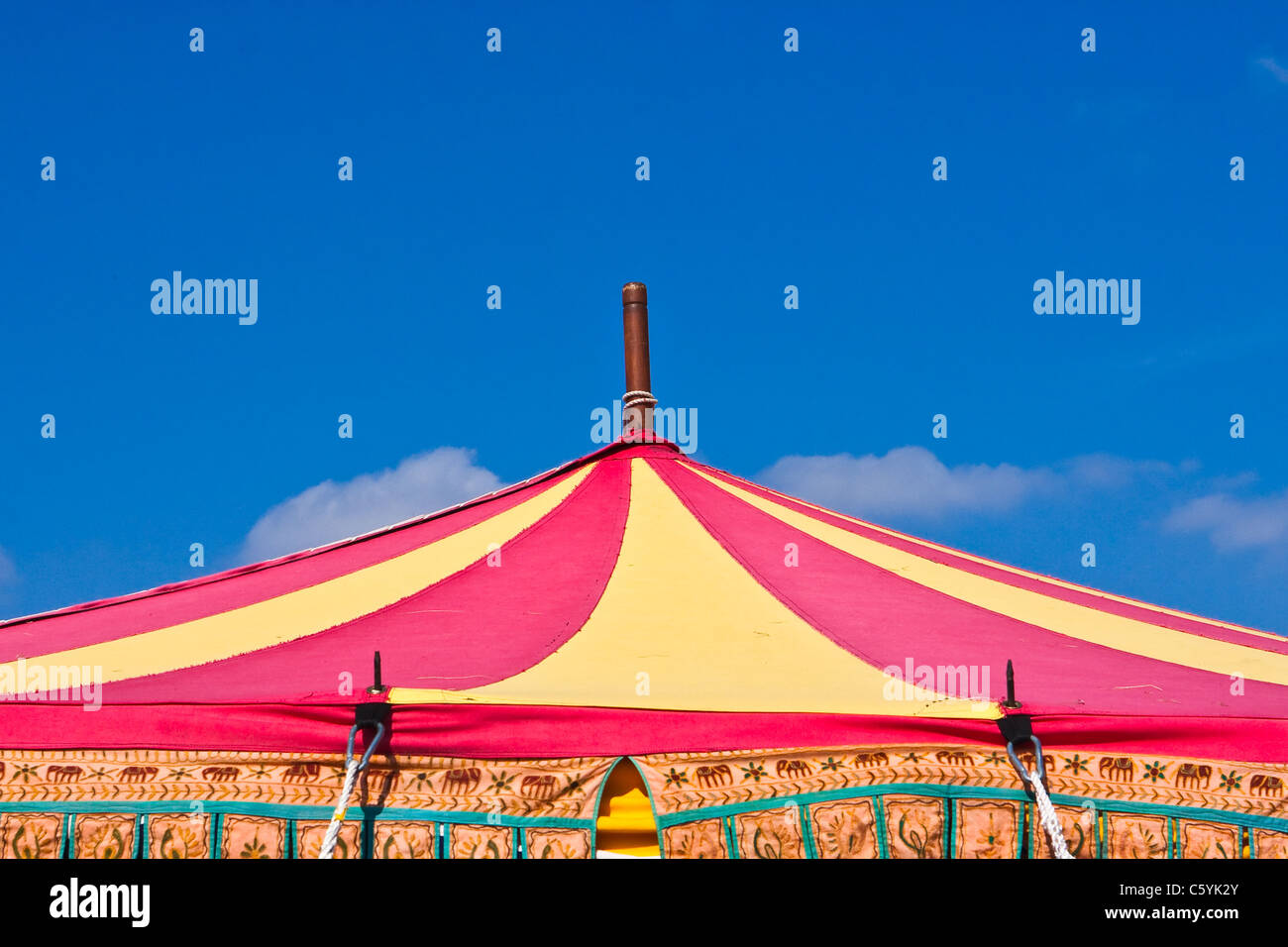 Un colorato luminosamente tenda del circo top contro un luminoso cielo blu Foto Stock