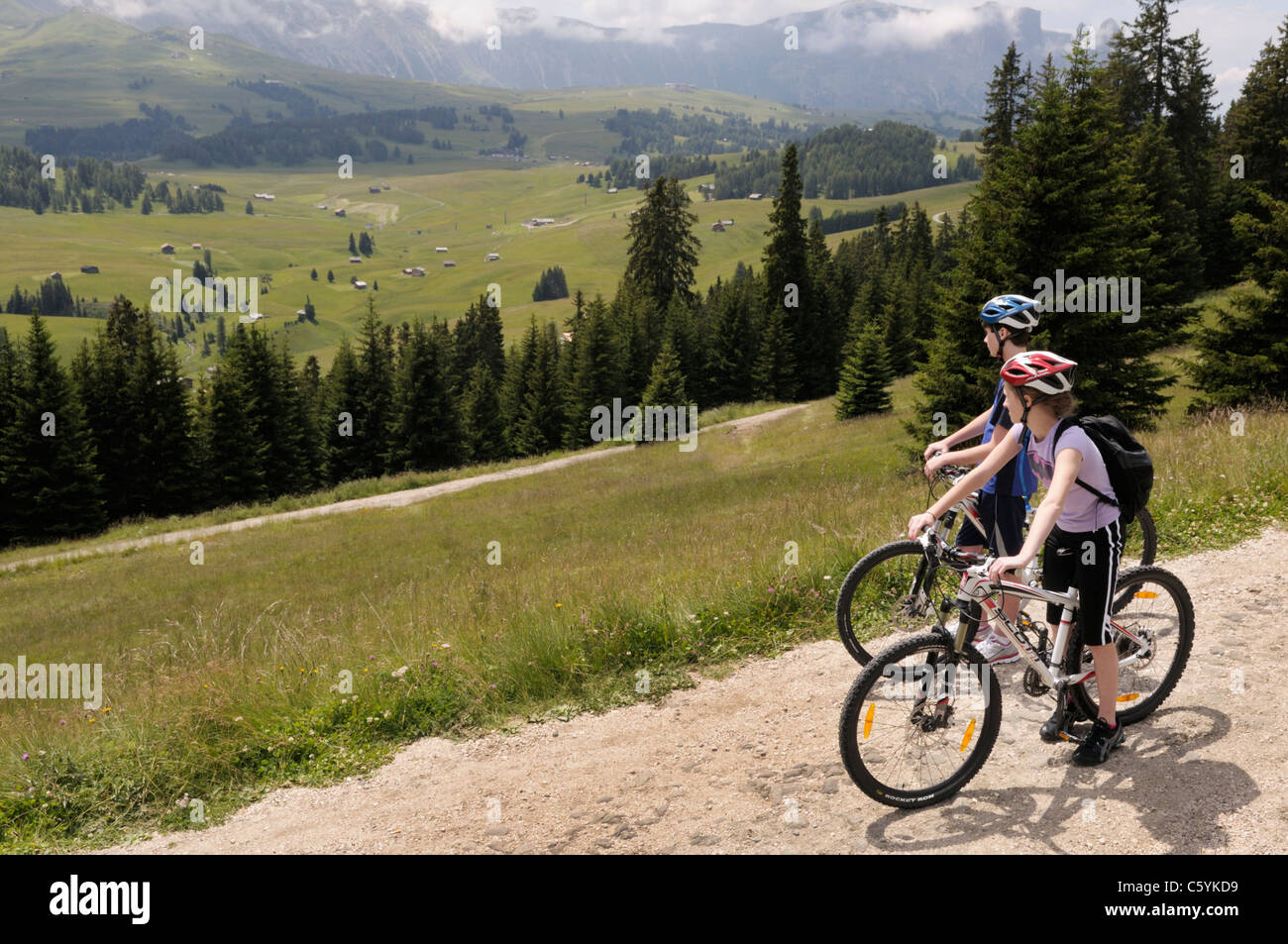 Un ragazzo e una ragazza, 14 e 12, sulle biciclette sull Alpe di Siusi vicino a Val Gardena, Italia. Foto Stock