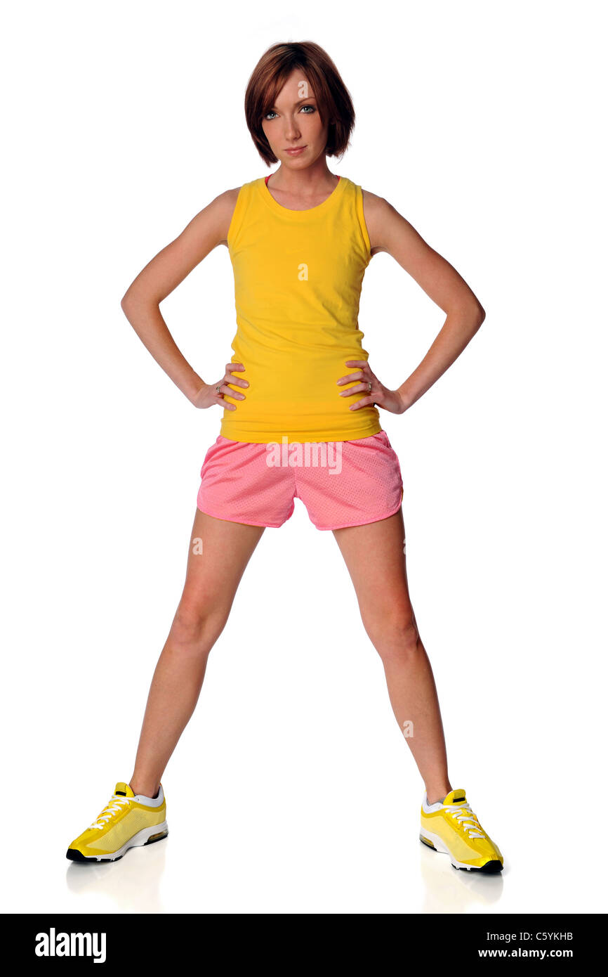 Giovane donna in abbigliamento atletico in piedi con le braccia akimbo isolate su sfondo bianco Foto Stock