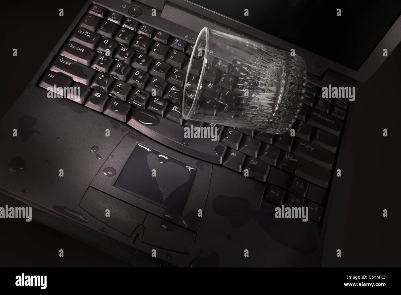 Un bicchiere di acqua accidentalmente rovesciato sulla tastiera del computer  portatile Foto stock - Alamy