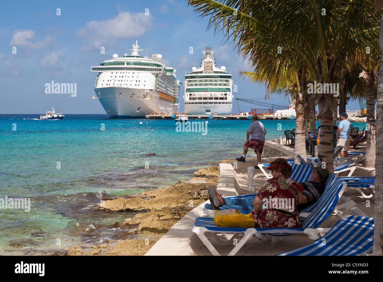 I turisti sulla spiaggia guarda la nave di crociera attività presso il porto di Cozumel, Messico nel Mar dei Caraibi Foto Stock