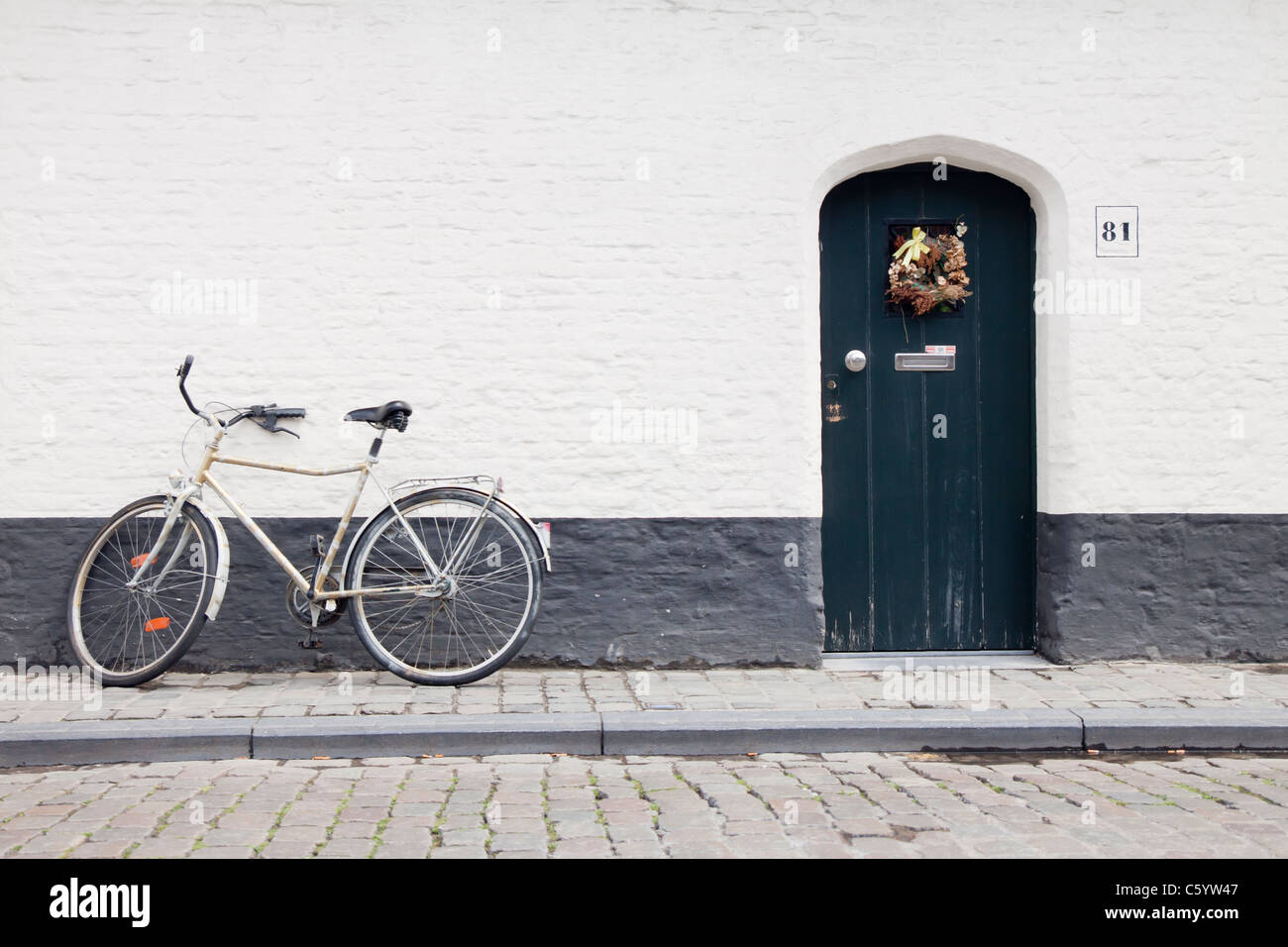 Una bicicletta tradizionale appoggiata contro una strada sul retro house di Bruges, Belgio. Foto Stock