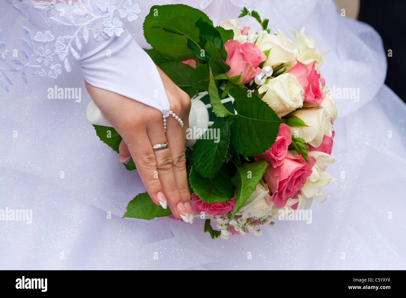 Sposa la mano con l'anello su un dito con il bouquet Foto Stock