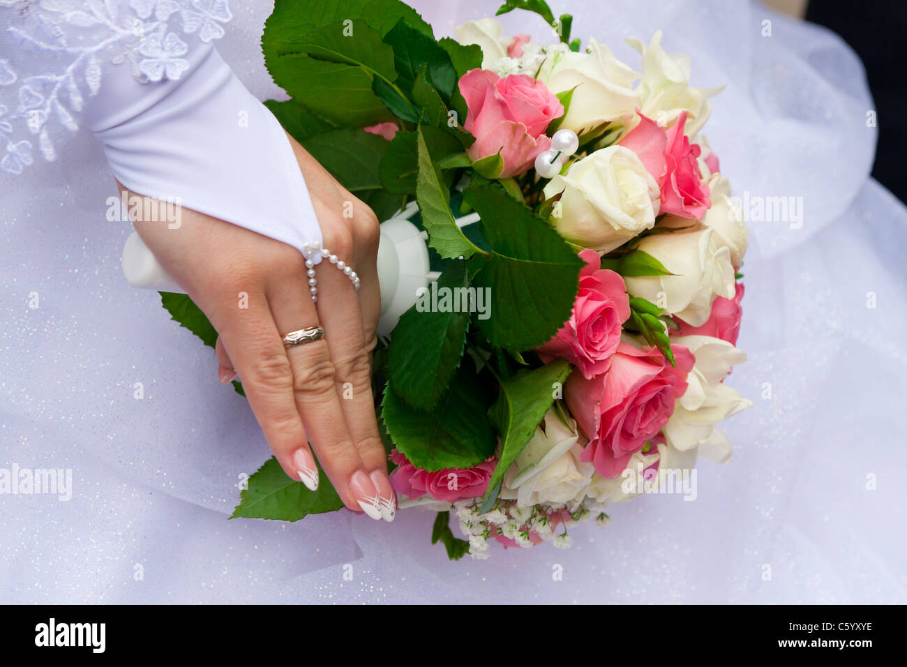 Sposa la mano con l'anello su un dito con il bouquet Foto Stock