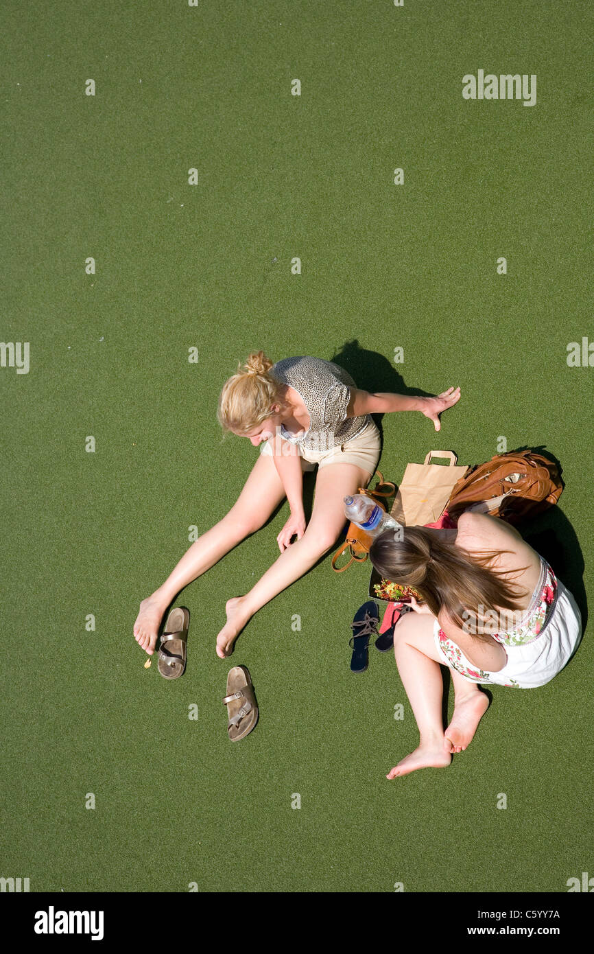 Coppia di donne rilassante sulla South Bank piazza sul tappeto verde erba Foto Stock