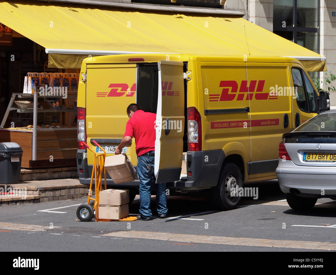 Corriere DHL consegna dei pacchi con il suo furgone giallo a Saumur, Valle della Loira, Francia Foto Stock