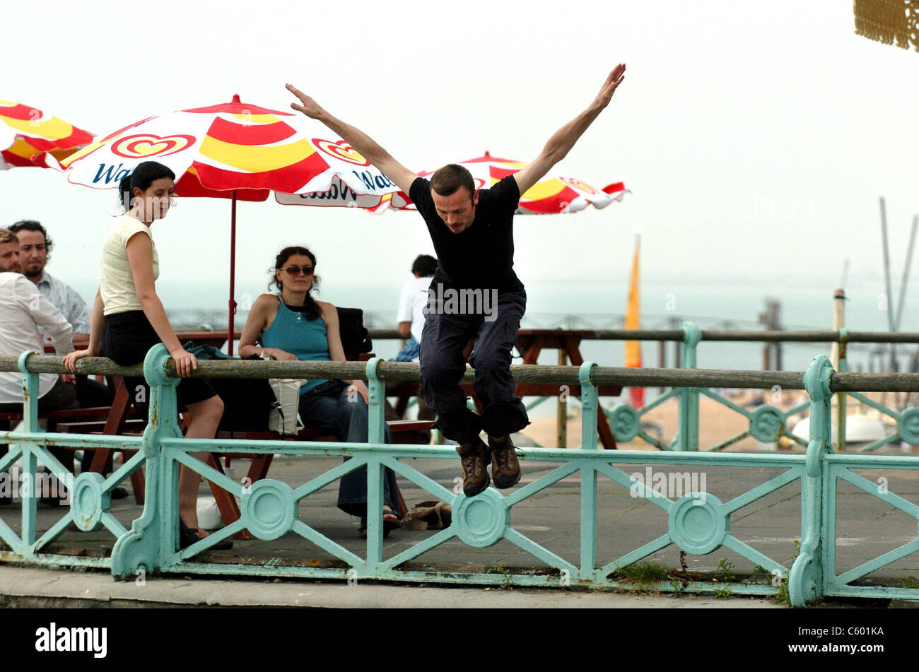 Free runner Alister O'Loughlin salti oltre i parapetti a goccia 12 piedi sul livello successivo lungo la Brighton Seafront oggi . Foto Stock