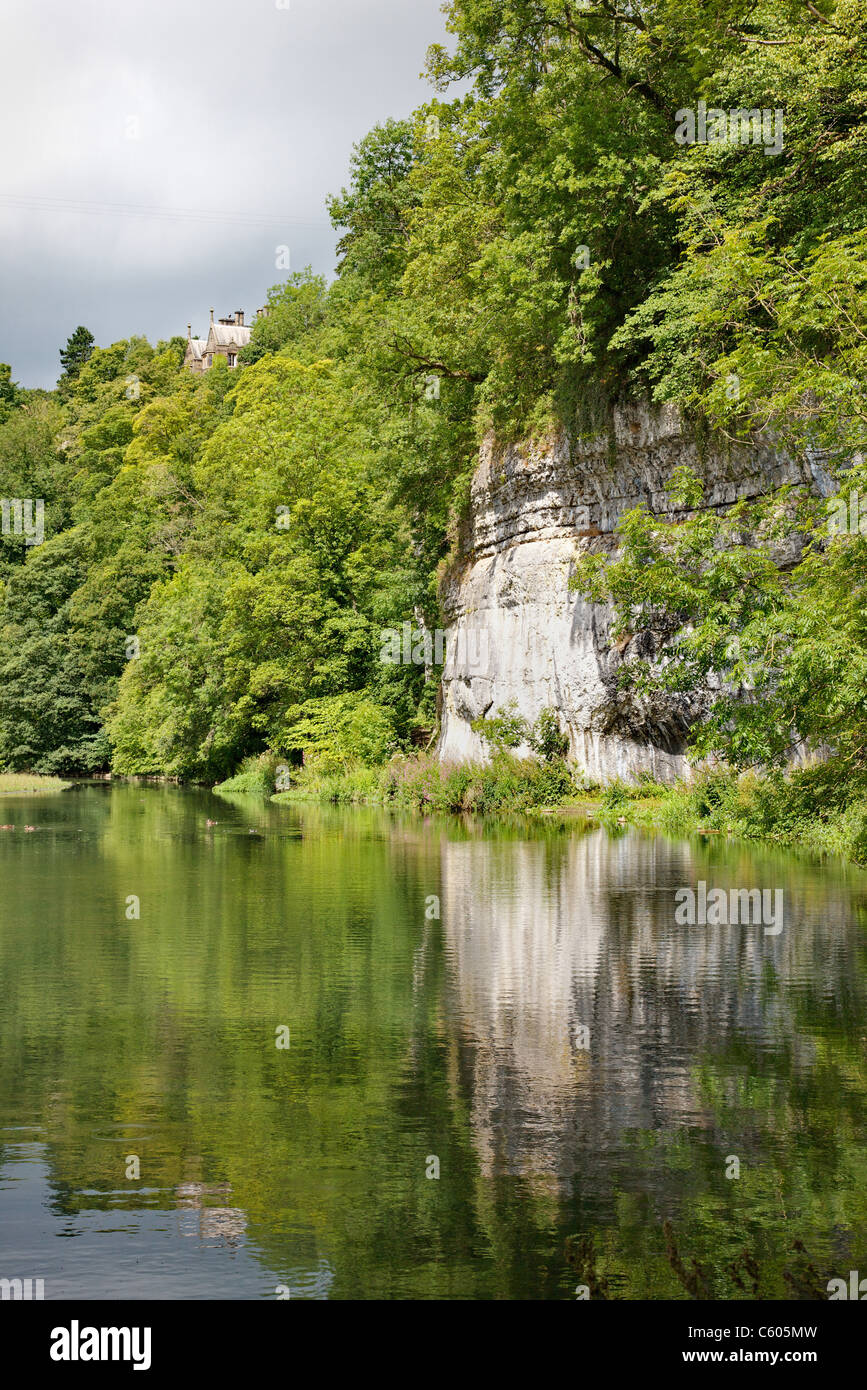 Il laghetto di mulino sul fiume Wye a Cressbrook Dale nel Derbyshire picco bianco con Cressbrook Hall alta sopra la valle Foto Stock