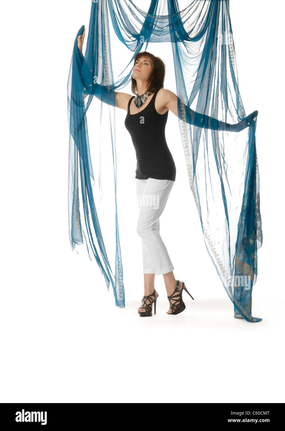 Immagine di moda di attraenti, eleganti donna nella sua 40s, indossando un abito semplice con elaborati collana e tacchi alti Foto Stock
